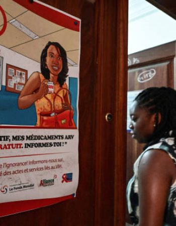 A woman walks past a poster on the fight against HIV-AIDS at the entrance to the headquarters of the platform of networks and umbrella organisations to attend a press conference on the effects of USAID cuts, in the commune of Cococdy in Abidjan on March 4, 2025. (Photo by Sia KAMBOU / AFP) (Photo by SIA KAMBOU/AFP via Getty Images)